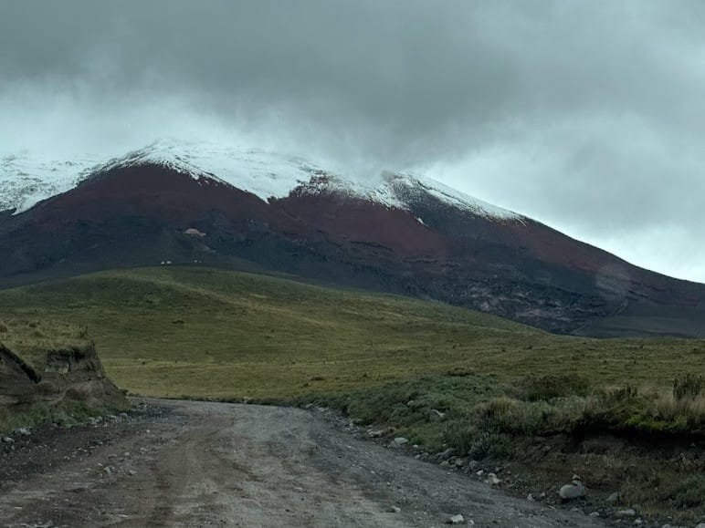 Cotopaxi volcano under heavy cloud, seen from a dirt road across the páramo in the Ecuadorian highlands