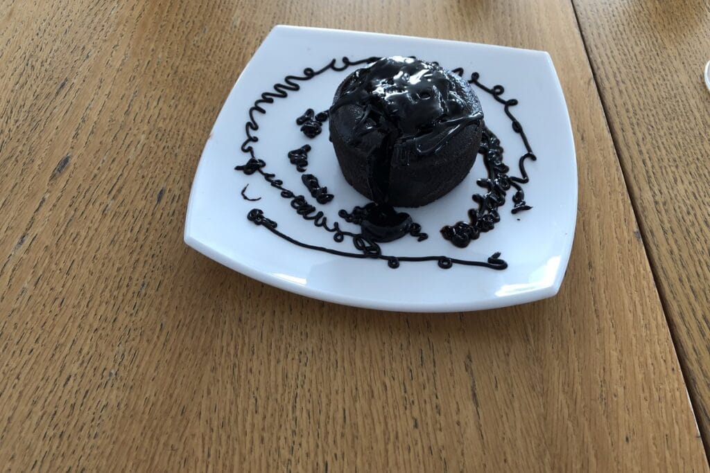 A molten chocolate cake on a white plate on a wooden table
