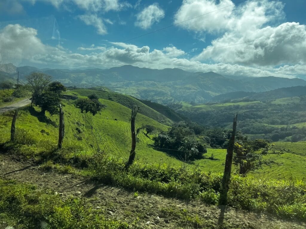 Green mountain pastures and ridges seen through a vehicle window on the road in Costa Rica
