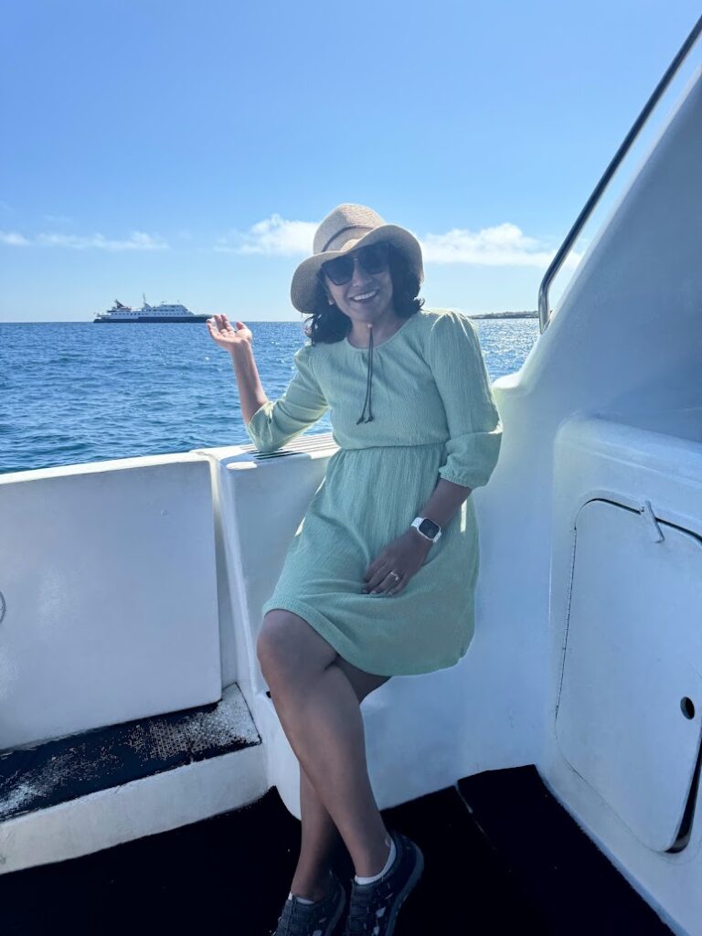 Milli on a yacht deck with a cruise ship on the horizon