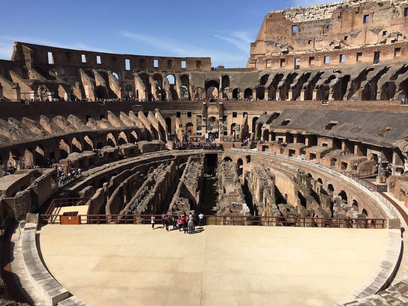 The interior of the Colosseum showing the arena floor, tiers and hypogeum under a blue sky