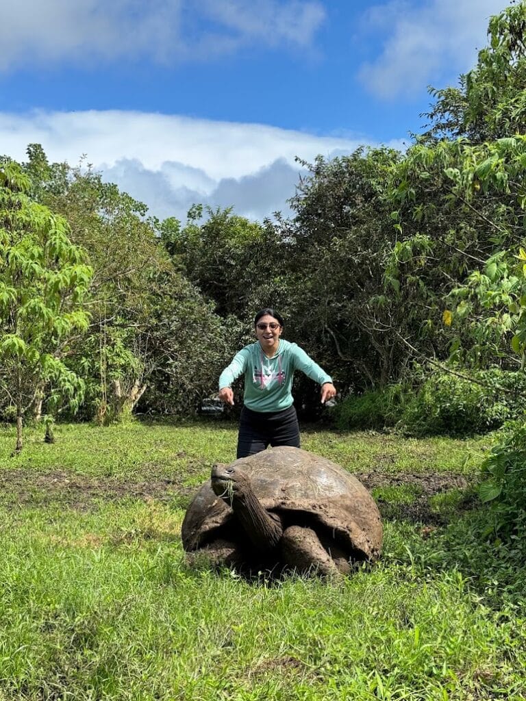 Milli Gupta of Wesley Chapel Travel standing beside a giant tortoise in the Santa Cruz highlands, Galápagos
