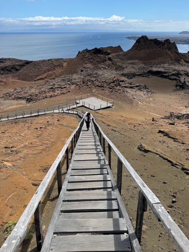 Wooden boardwalk descending across red and orange volcanic ground on Bartolomé island, Galápagos