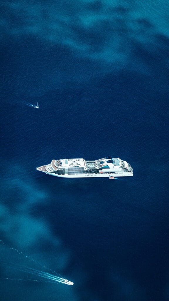 Aerial view of a small luxury cruise ship sailing across deep blue open ocean