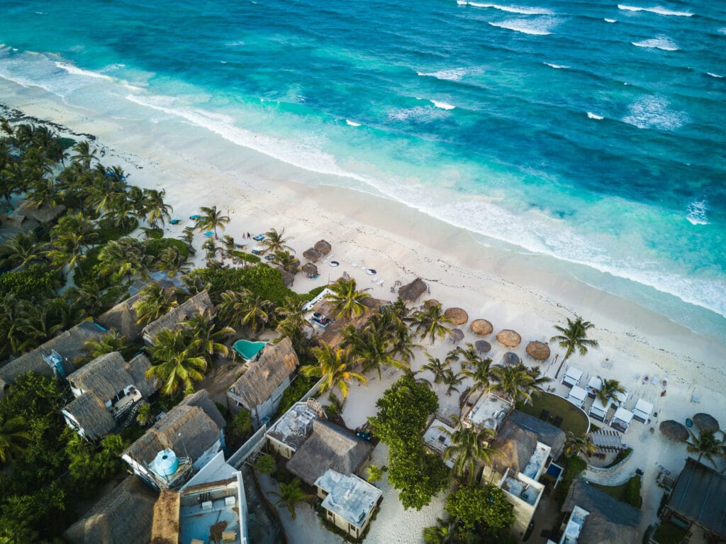Thatched beachfront villas along white sand and turquoise water