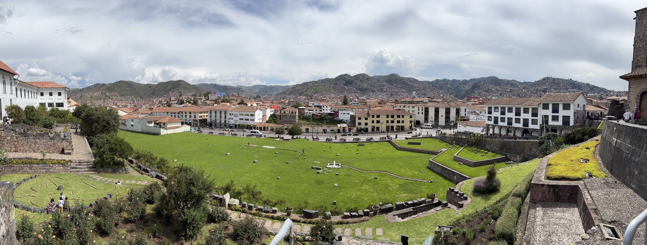 A wide view over the rooftops of Cusco, Peru, with green hills behind.