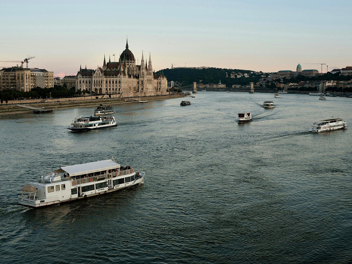 River cruise boats on the Danube at dusk passing the Hungarian Parliament in Budapest