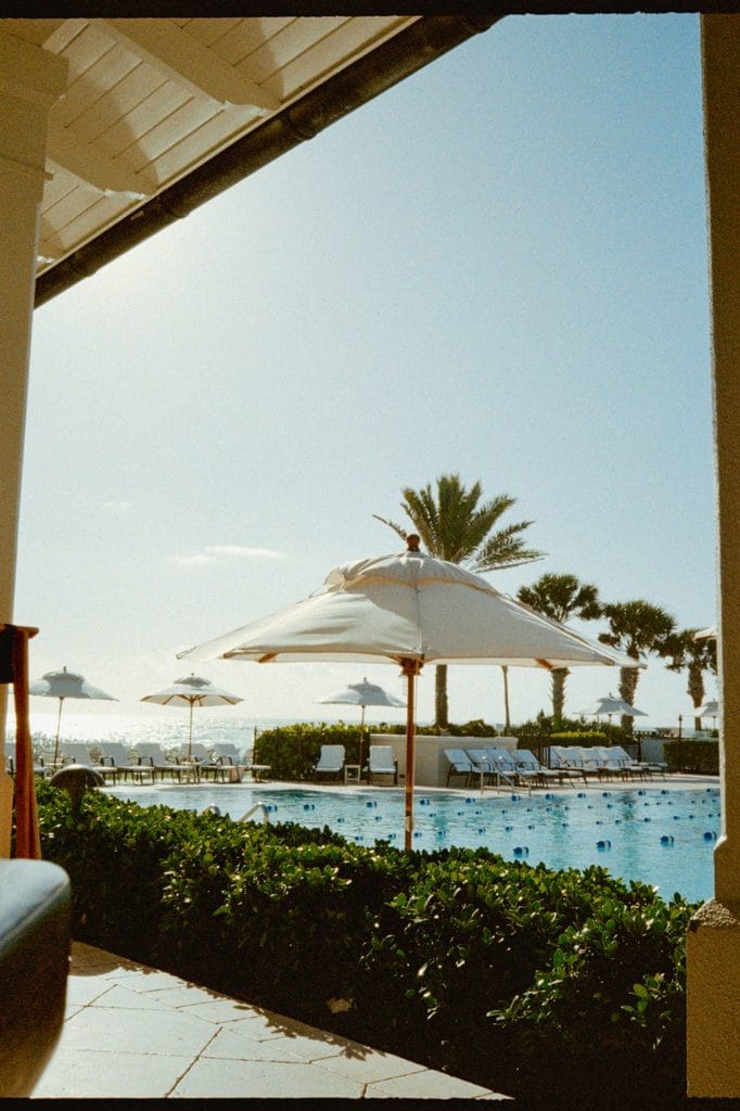 Poolside loungers and white umbrellas overlooking the ocean at a coastal resort