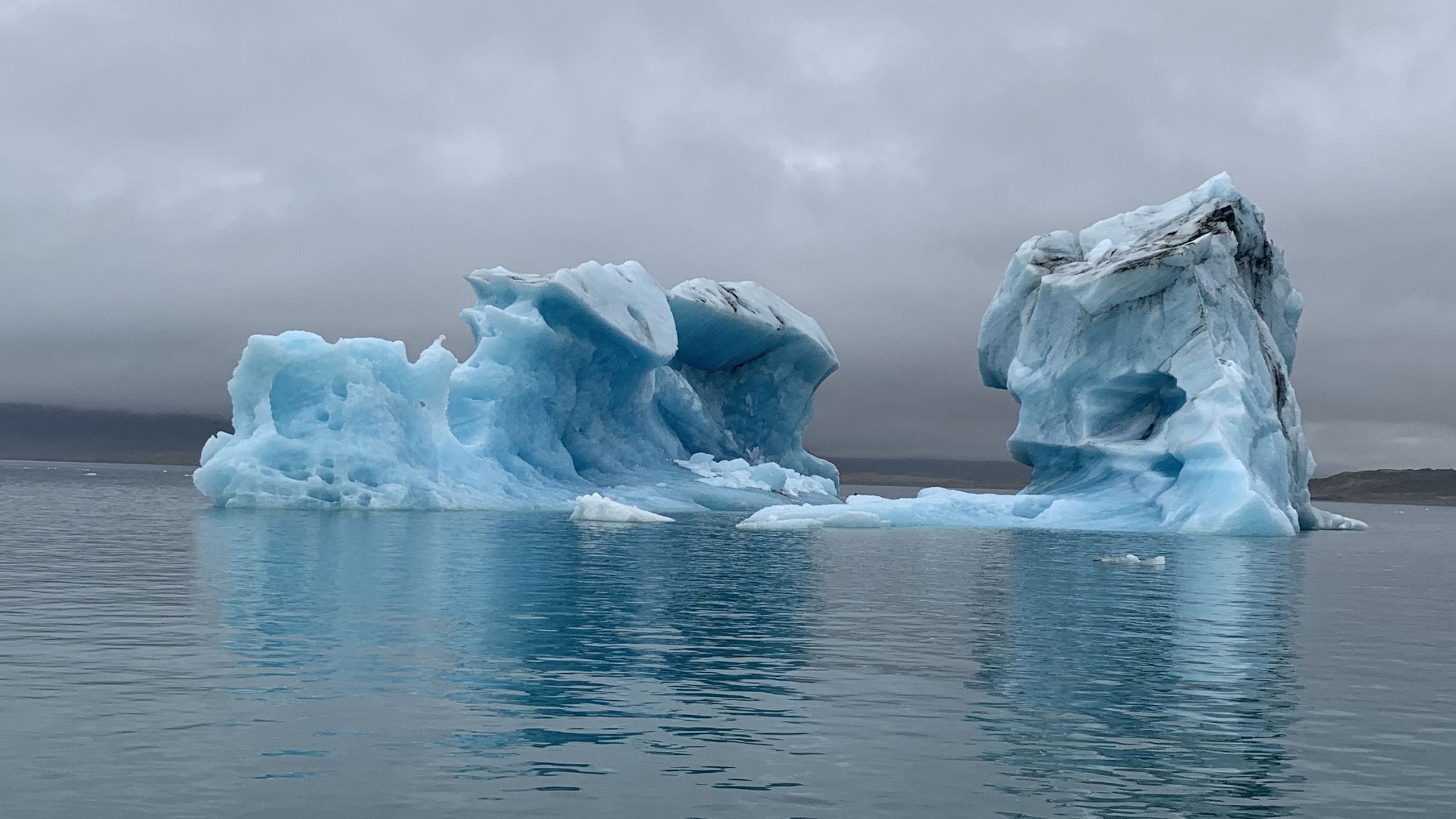 Blue icebergs floating in Jökulsárlón glacier lagoon in southeast Iceland under a grey August sky