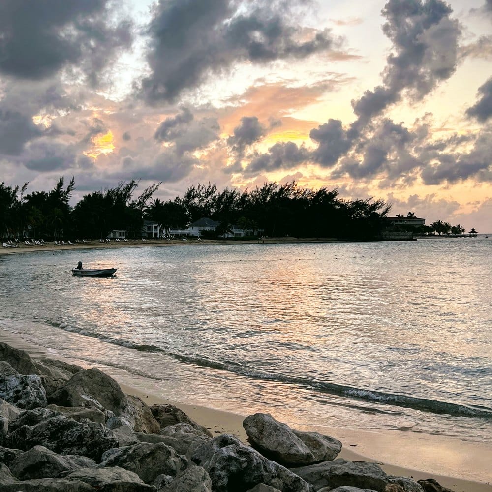 Boat off a rocky shore at dusk, Jamaica