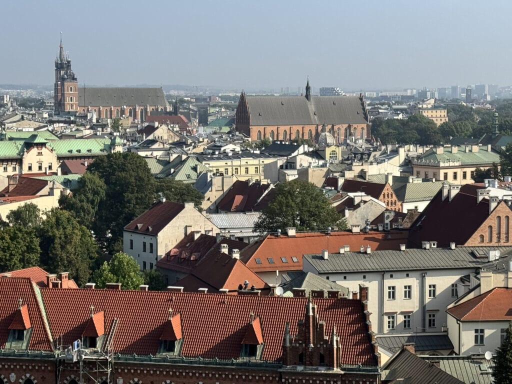 Kraków rooftops in morning haze with the spire of St Mary's Basilica and a large brick church beyond