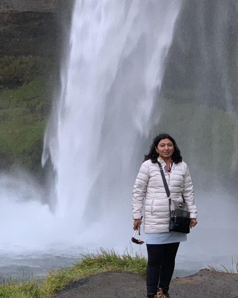 Milli Gupta, travel advisor, standing in front of Seljalandsfoss waterfall in southern Iceland