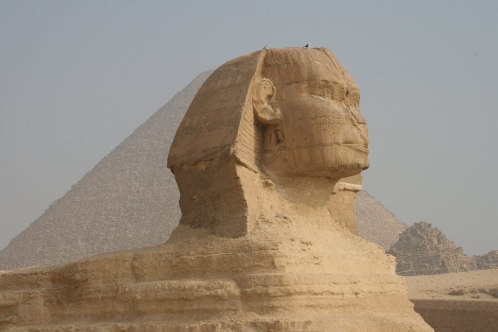 The Great Sphinx of Giza in profile with a pyramid rising behind it