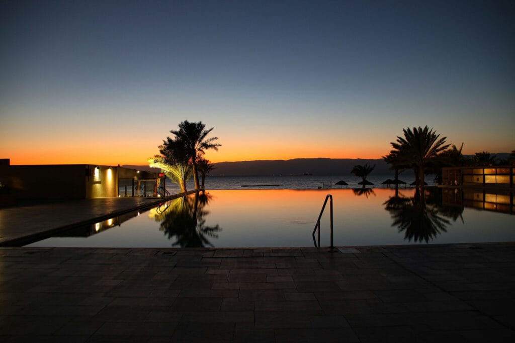 Infinity pool and palms reflecting a sunset sky at a coastal resort