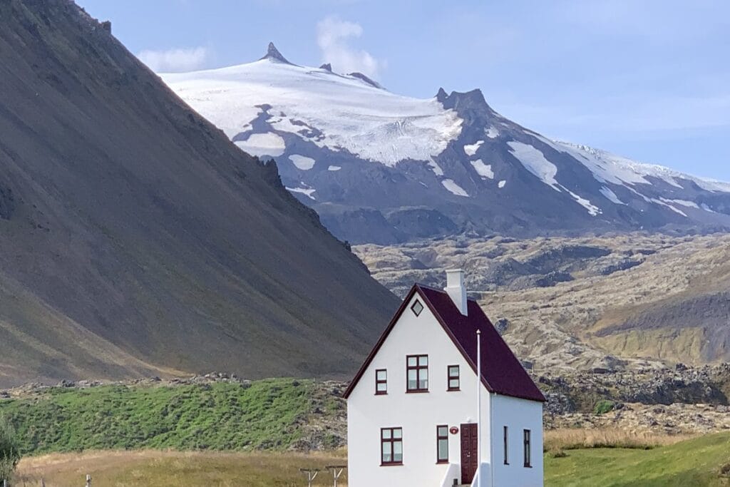 White farmhouse with a red roof below the Snæfellsjökull glacier at Arnarstapi on Iceland's Snæfellsnes peninsula
