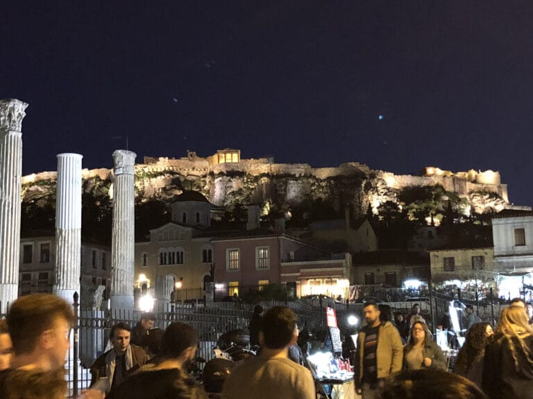 The illuminated Acropolis at night behind the Corinthian columns of Hadrian's Library in the Monastiraki district of Athens.