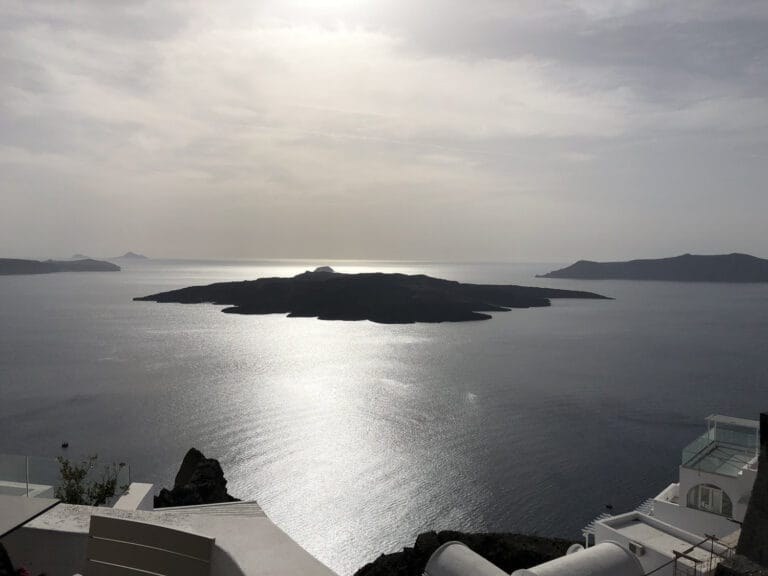 A sweeping view over the Aegean toward the volcanic islands at the center of the Santorini caldera.