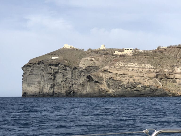 A view from the water of the towering volcanic cliffs near the Akrotiri peninsula on Santorini's southern coast.