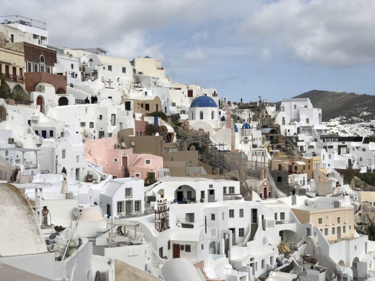 Whitewashed houses and blue-domed churches built into the cliffside of Oia village, Santorini.